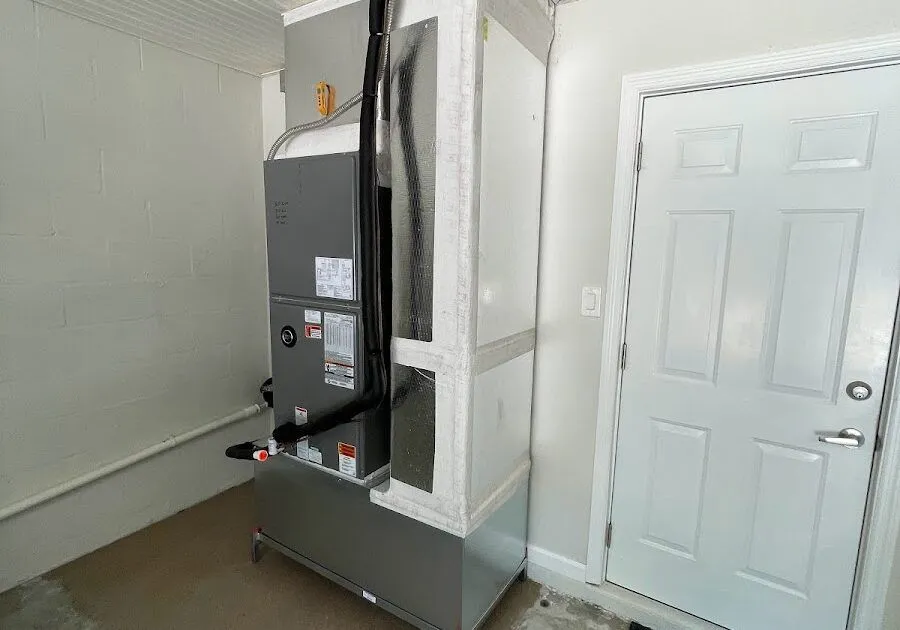A professional vertical air handler installation in a garage featuring custom ductwork plenum and insulated refrigerant lines.