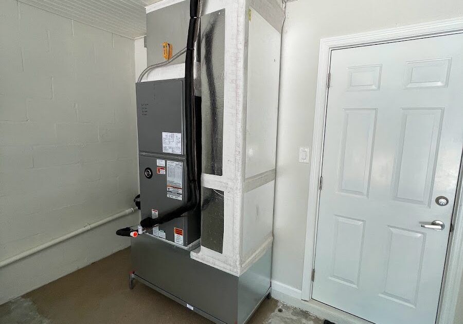 A professional vertical air handler installation in a garage featuring custom ductwork plenum and insulated refrigerant lines.