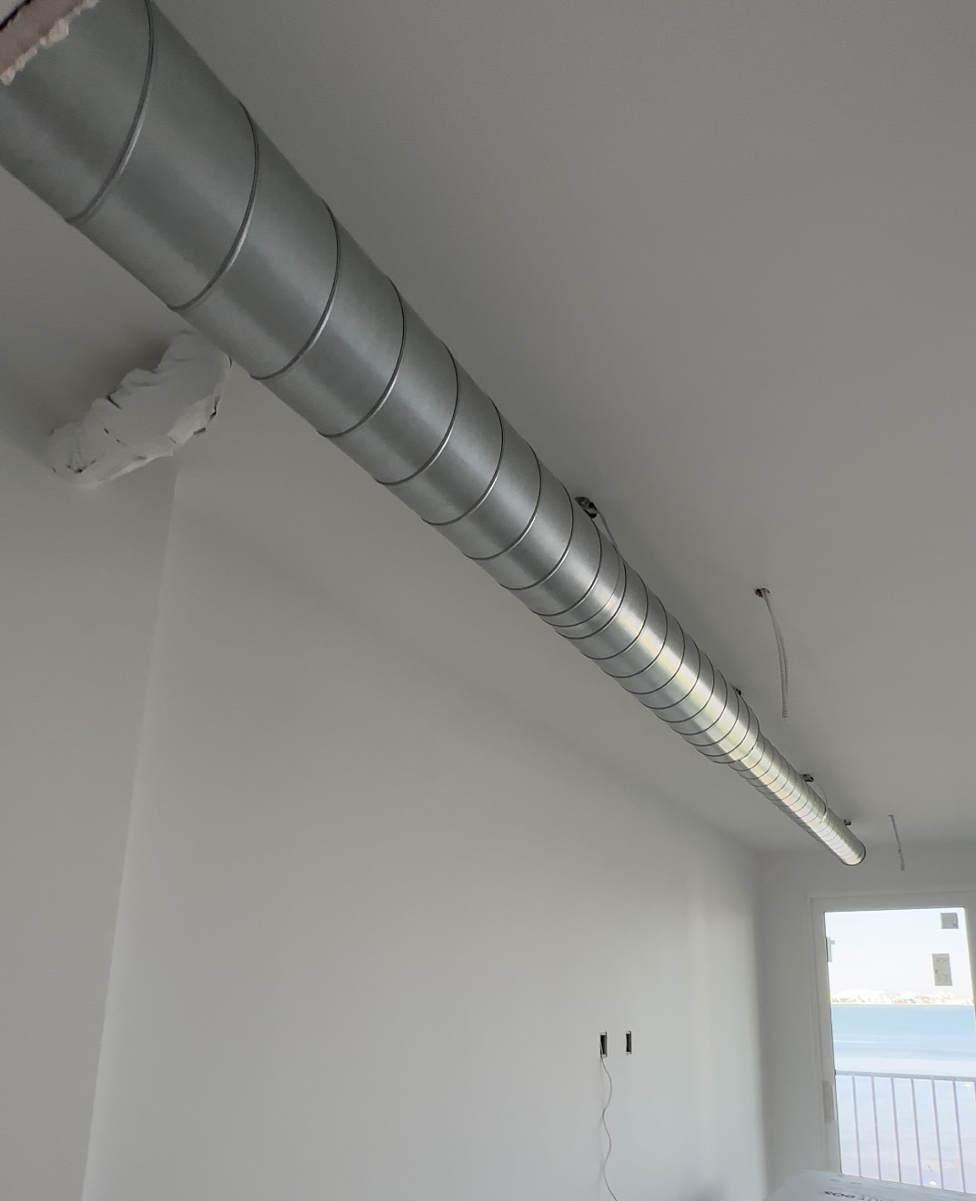 Exposed spiral HVAC ductwork installed in modern home interior for efficient airflow and contemporary design