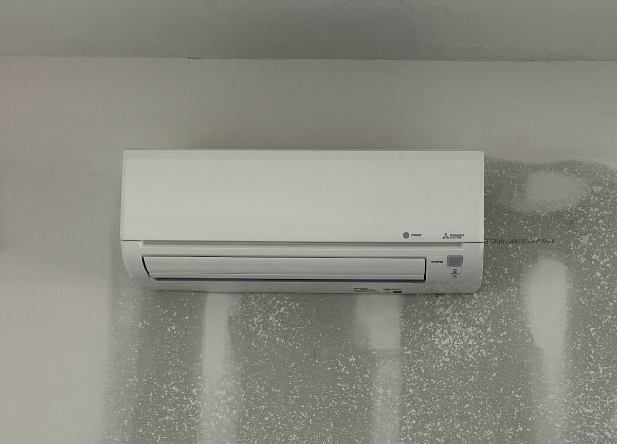 A Mitsubishi Electric and Trane ductless mini-split indoor wall-mounted air handler installed on a white wall during a home renovation.