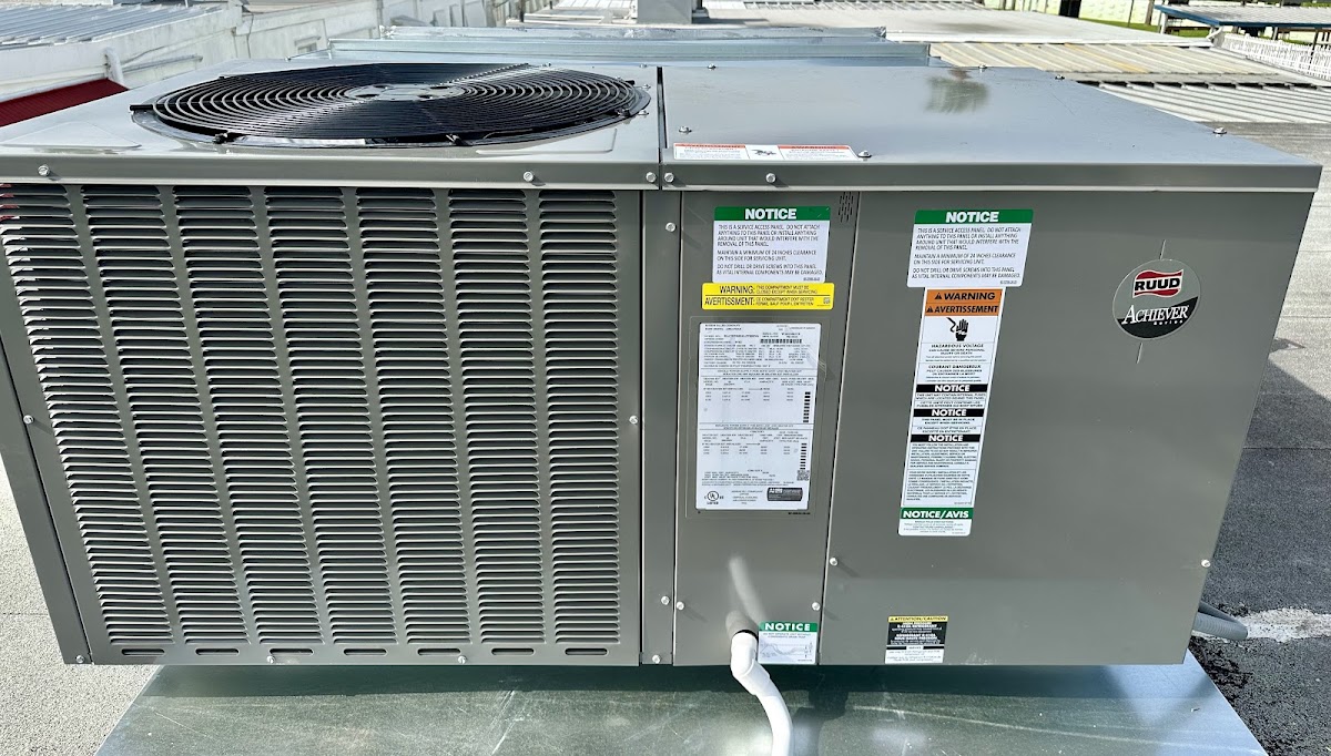 Exterior view of a RUUD Achiever series packaged HVAC system showing the top condenser fan grille and side service access panels.