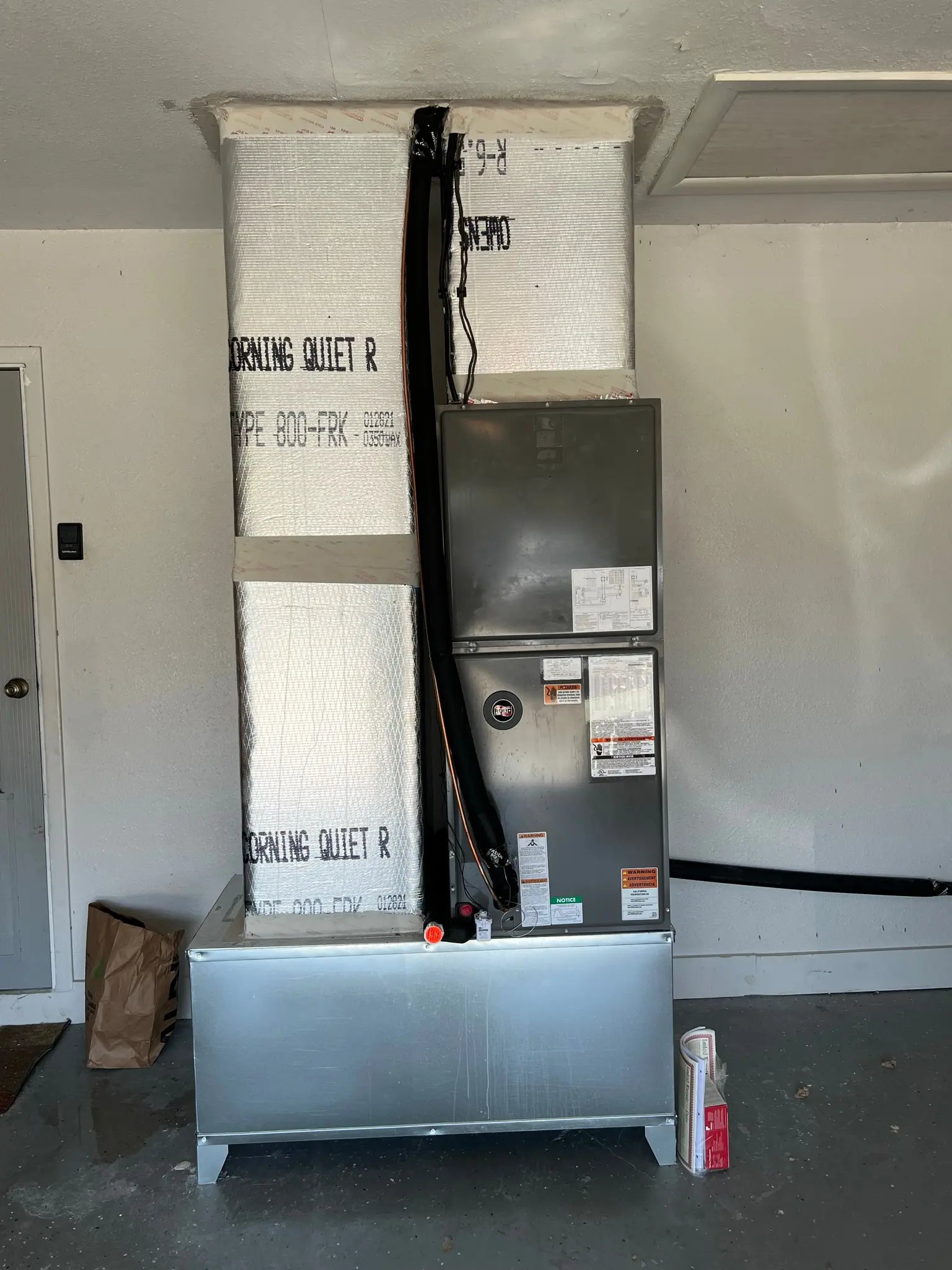 HVAC system installation in a residential garage, featuring a modern air handling unit with insulated ductwork for efficient cooling.