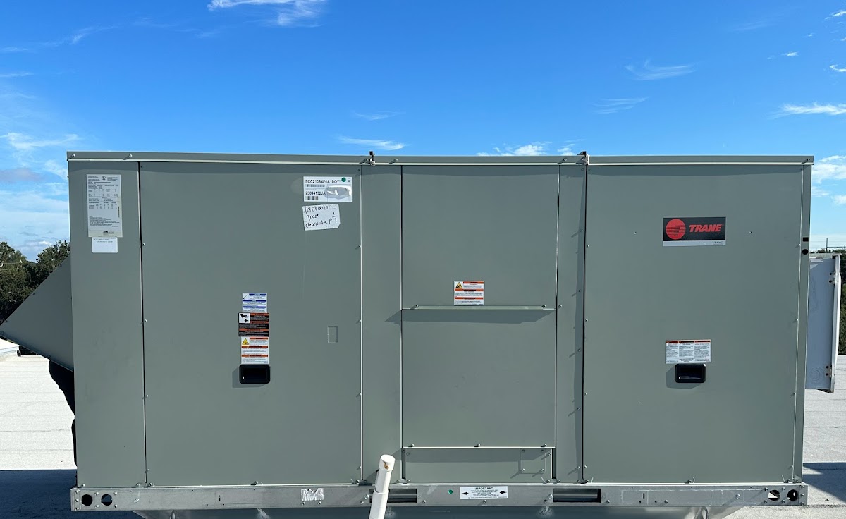 Front view of a large Trane commercial rooftop unit showing manufacturer labels and access panels, part of a commercial cooling system replacement.