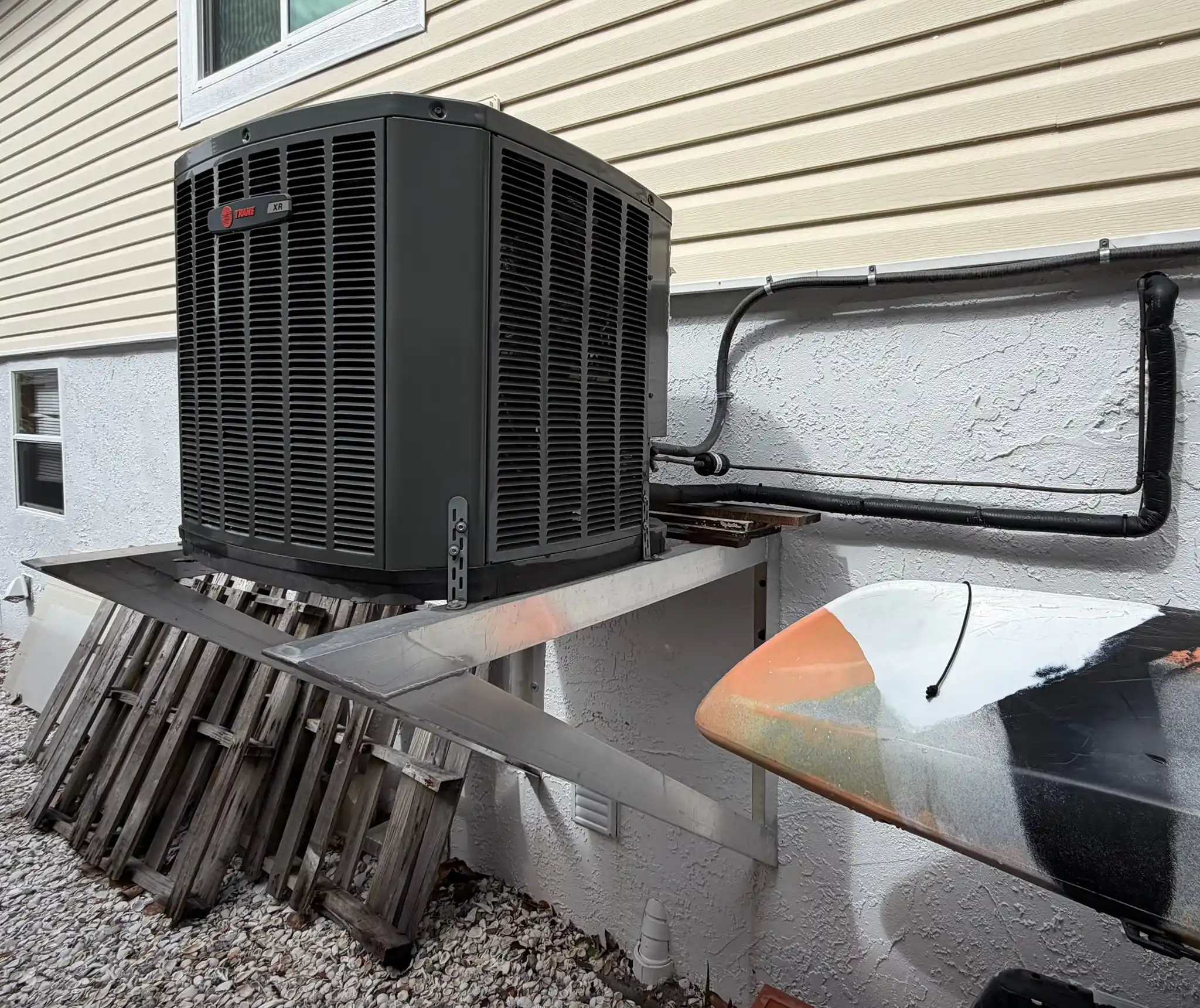 Exterior Trane XR air conditioning condenser unit mounted on a wall bracket for a residential home, serviced by M&R Air Conditioning.