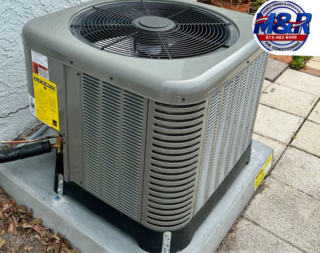 Outdoor residential HVAC air conditioning unit installed on a concrete pad with M&R Air Conditioning logo visible, showing a standard single-family home AC system setup in Tampa, Florida
